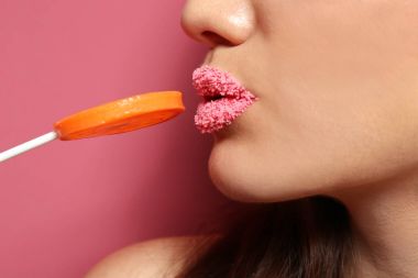 Dudaklar yakınındaki lolipop tutan güzel genç kadın 