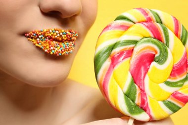 Dudaklar yakınındaki lolipop tutan güzel genç kadın 