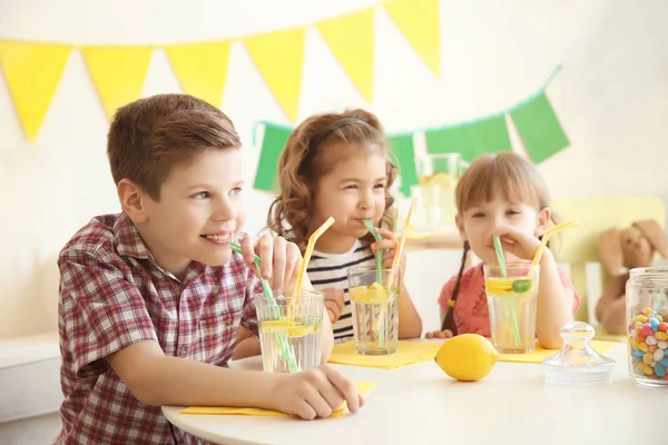 Schattig weinig kinderen drinken limonade aan tafel — Stockfoto