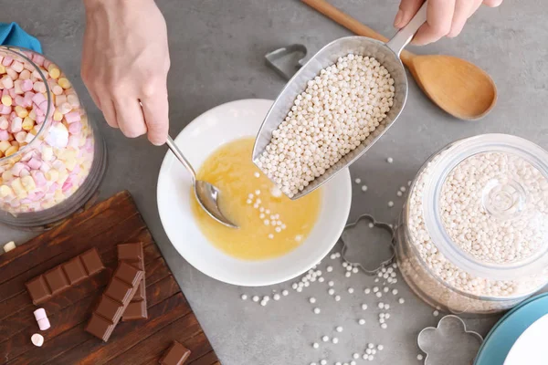 Женщина добавляет хрустящие шарики риса в керамическую миску — стоковое фото