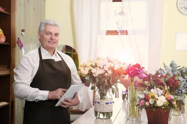 Senior male florist with tablet at flower shop, Consulting service concept
