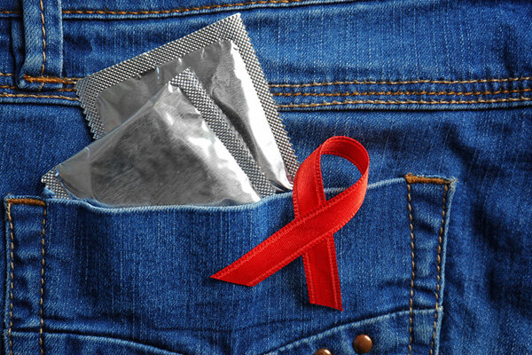 Condoms in pocket of jeans and red ribbon