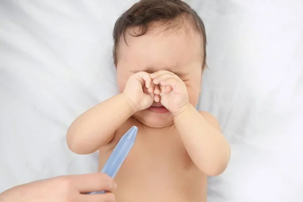 Moeder gebruik van nasale aspirator voor schattige kleine baby liggend op bed thuis. Health care concept — Stockfoto