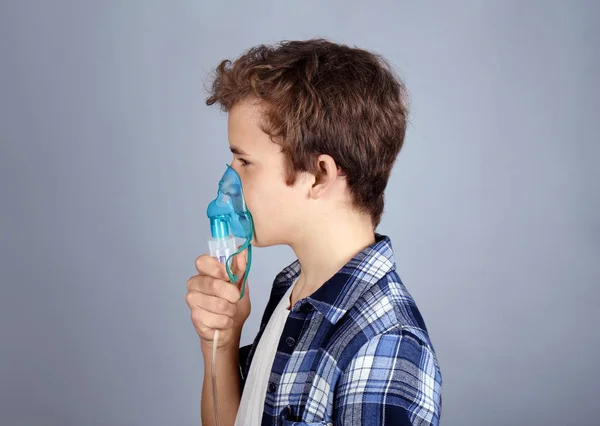Niño joven usando nebulizador para asma y enfermedades respiratorias sobre fondo claro — Foto de Stock