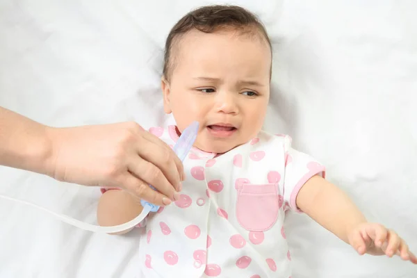 Moeder gebruik van nasale aspirator voor schattige kleine baby liggend op bed thuis. Health care concept — Stockfoto