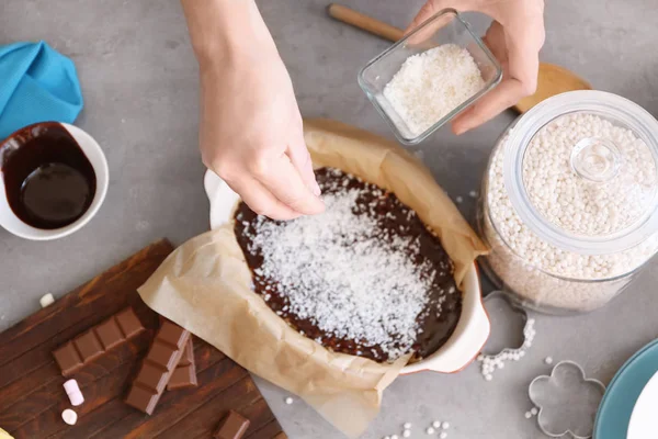 Mujer rociando coco desecado sobre el postre de arroz — Foto de Stock