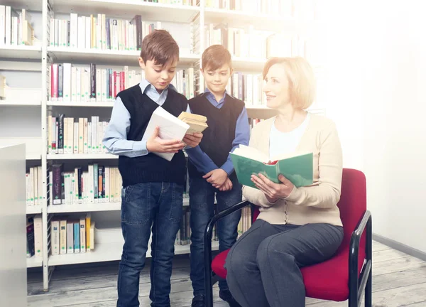 Professor e meninos com livros na biblioteca da escola — Fotografia de Stock