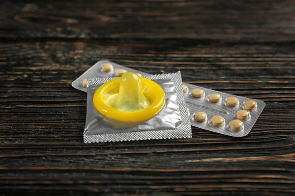 Prezerwatywy i tabletki antykoncepcyjne na podłoże drewniane — Zdjęcie stockowe