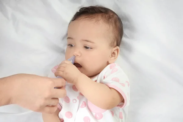 Mãe usando aspirador nasal para bebê pequeno bonito deitado na cama em casa. Conceito de saúde — Fotografia de Stock