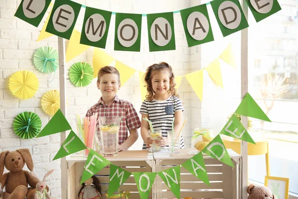 Милые маленькие дети продают лимонад за прилавком — стоковое фото