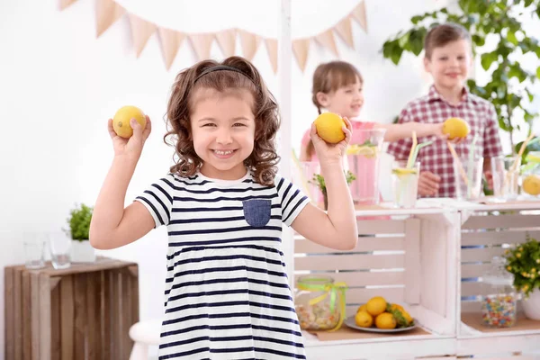 Holding arka plan üzerine limon ve çocuklarla bulanık stand sevimli küçük kız — Stok fotoğraf