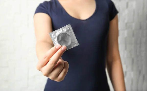 Woman holding condom in hand — Stock Photo, Image