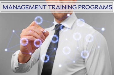 Yönetim eğitim programları kavramı. Genç adam gri arka plan karşı sanal ekran ile çalışma