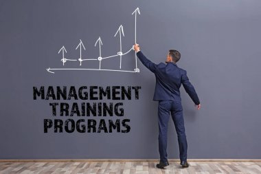Yönetim eğitim programları kavramı. Genç adam çizim diyagram üzerinde gri duvar