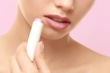 Closeup view of beautiful young woman applying lipstick, color background clipart