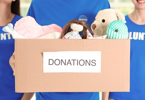 Young volunteers with box of donations indoors, closeup — Stock Photo, Image