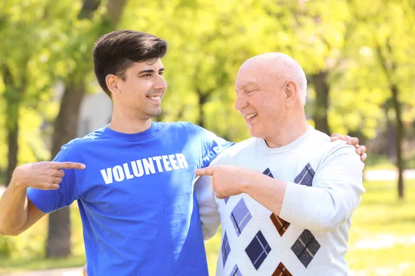 Fiatal és idősebb ember mutatva póló szöveggel önkéntes szabadban — Stock Fotó
