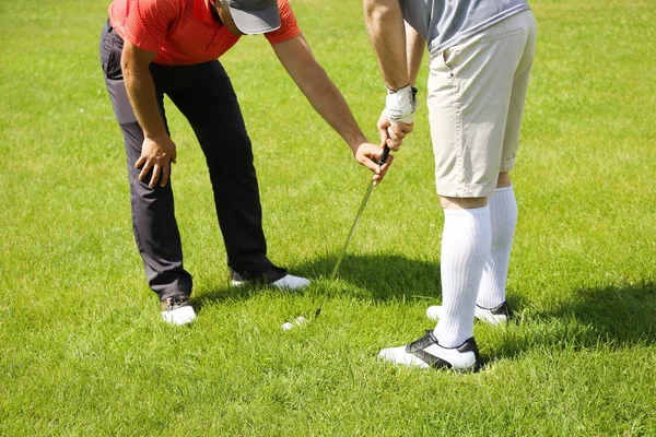 Caddy nauczania młodego człowieka, aby zagrać w golfa na kurs w słoneczny dzień — Zdjęcie stockowe