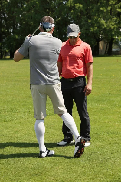 Caddy onderwijs jonge man te golfen op de cursus in zonnige dag — Stockfoto