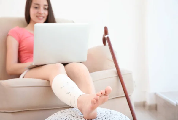 Jovem com laptop e perna enfaixada — Fotografia de Stock