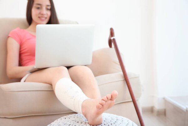 young woman with laptop and bandaged leg