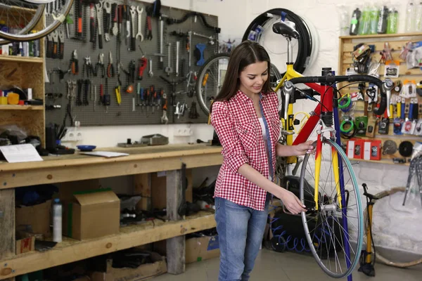 Mujer que trabaja en taller de reparación de bicicletas — Foto de Stock