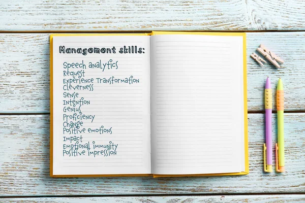 List of MANAGEMENT SKILLS written in notebook on wooden background