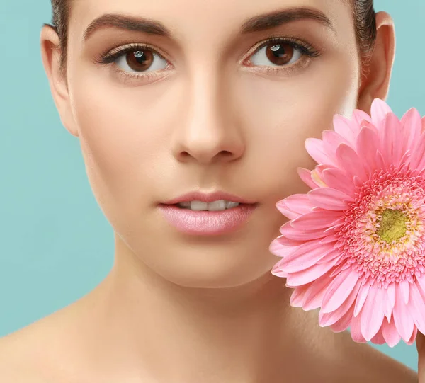 Vista de cerca de la hermosa mujer joven con maquillaje de labios naturales y flor en el fondo de color — Foto de Stock