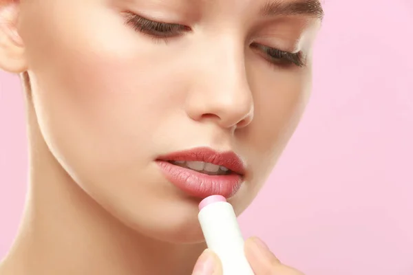 Closeup view of beautiful young woman applying lipstick, color background — Stock Photo, Image