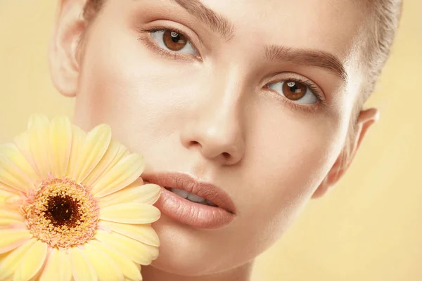 Vista de cerca de la hermosa mujer joven con maquillaje de labios naturales y flor en el fondo de color —  Fotos de Stock