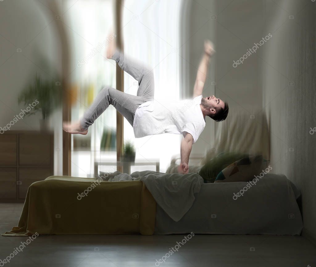 Young man levitating over bed while having dream about falling, Sleep paralysis concept