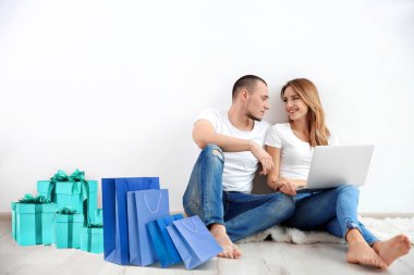 Internet alışveriş kavramı. Dizüstü bilgisayar ve Satınalmalar evde duvarının yakınında oturan genç Çift