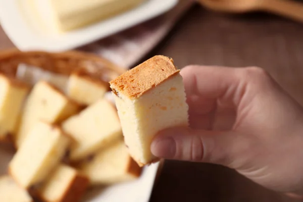 Vrouw houdt van boter taart stuk boven tafel — Stockfoto