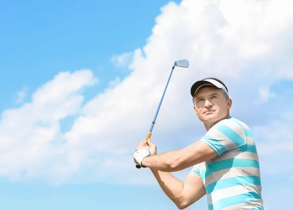 Молодой человек играет в гольф на поле в солнечный день — стоковое фото
