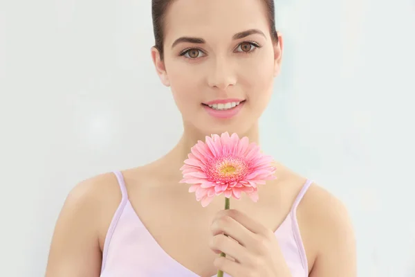 Vista close-up da bela jovem com maquiagem lábios naturais e flor no fundo branco — Fotografia de Stock