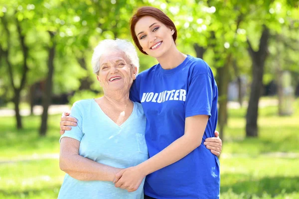 Молодая женщина-волонтер обнимает пожилую женщину на улице — стоковое фото