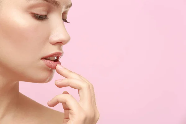 Vista de cerca de la hermosa mujer joven con maquillaje natural tocando los labios en el fondo de color — Foto de Stock