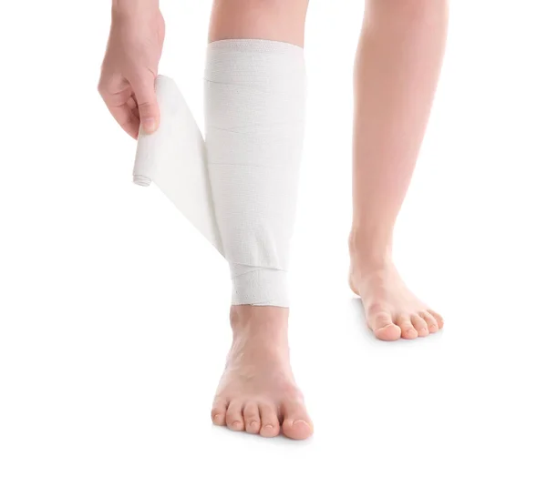Jovem aplicando bandagem na perna — Fotografia de Stock