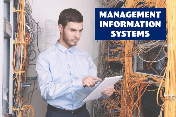 Concept of management information systems. Young engineer with tablet in server room