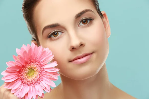 Closeup view of beautiful young woman with natural lips makeup and flower on color background — Stock Photo, Image