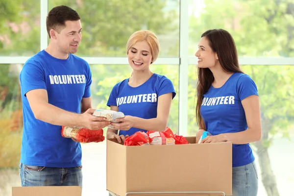 Молодые добровольцы с коробкой пожертвований в помещении — стоковое фото