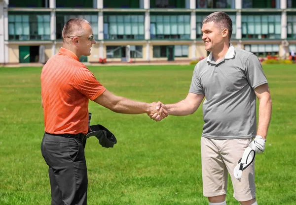 Jonge mannen handen schudden op golfbaan in zonnige dag — Stockfoto