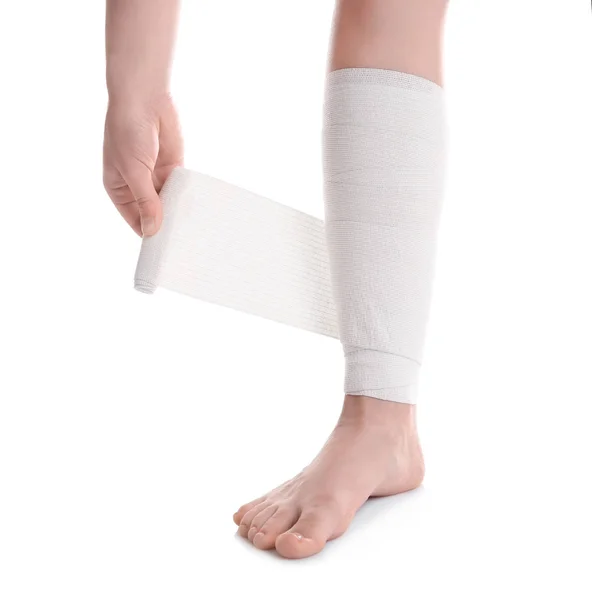 Jovem aplicando bandagem na perna — Fotografia de Stock