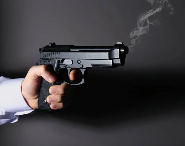 Man håller rykande pistol på mörk bakgrund — Stockfoto