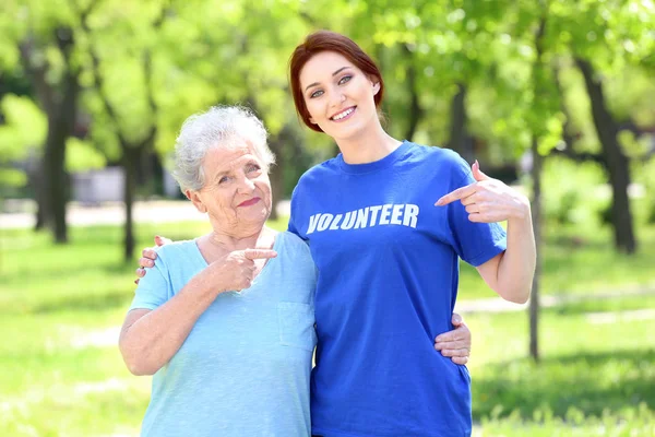 Açık havada gönüllü genç ve üst düzey kadın t-shirt metin ile işaret
