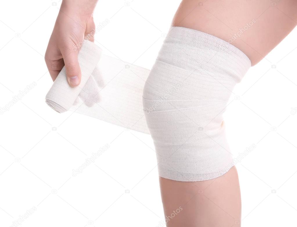 Young woman applying bandage onto leg