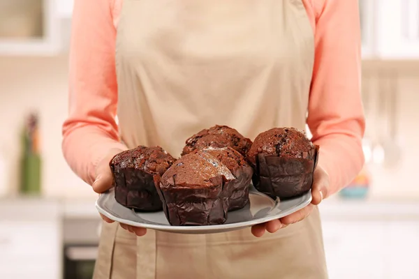 Woman holding plate with chocolate muffins — Stock Photo, Image