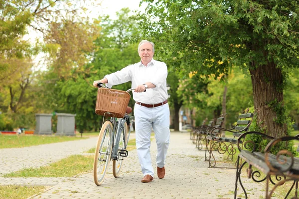 Uomo anziano a piedi con bicicletta nel parco — Foto Stock