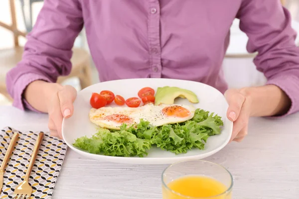 Женщина держит тарелку с яичницей и овощами — стоковое фото