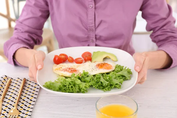 Woman holding plate of fried eggs and vegetables — Stock Photo, Image